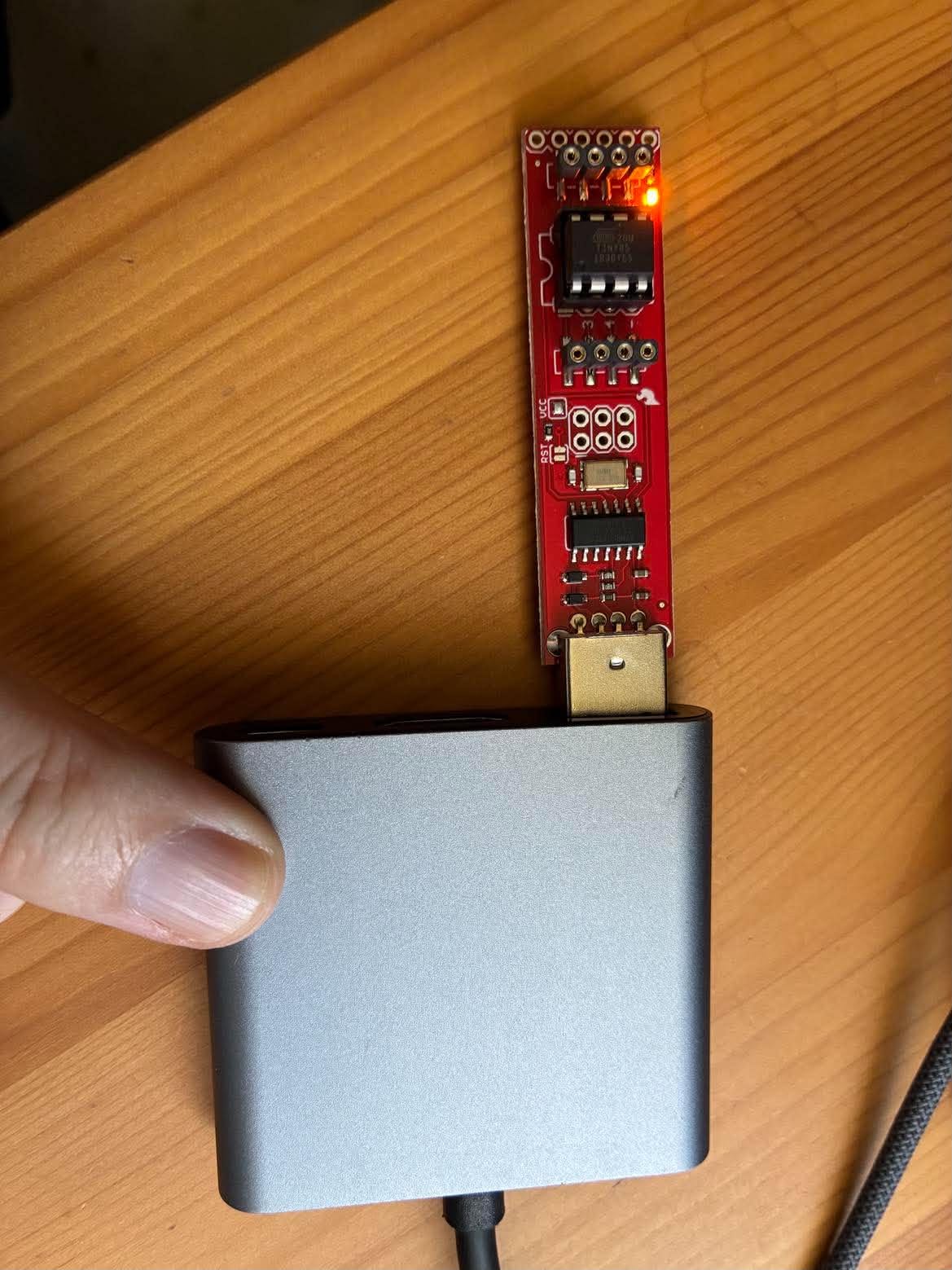 The programmer on a USB-C hub with its amber LED lit once it has power